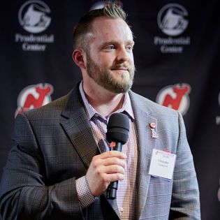 Chris speaking to a group in front of a logo backdrop